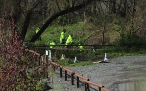 Police around the banks of the Tukituki River near Havelock North, near where a burned out car was found.