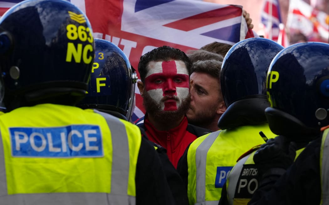 A person wears St George's Cross face paint as supporters of British far-right activist Tommy Robinson whose real name is Stephen Yaxley-Lennon, gather during a 'Free speech' march, in central London on September 13, 2025. (Photo by CARLOS JASSO / AFP)