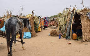 Sudanese refugees who crossed into Chad set up shelter at a camp in Koufroun, near Echbara, on May 1, 2023. Hundreds of Sudanese, most of them women and children, each day cross a small, dry stream to find safety in neighbouring Chad. At least 20,000 people had found refuge at a makeshift camp in the Chadian border village of Koufroun, according to the United Nations refugee agency UNCHR, which manages their influx along with other UN agencies. (Photo by Gueipeur Denis SASSOU / AFP)