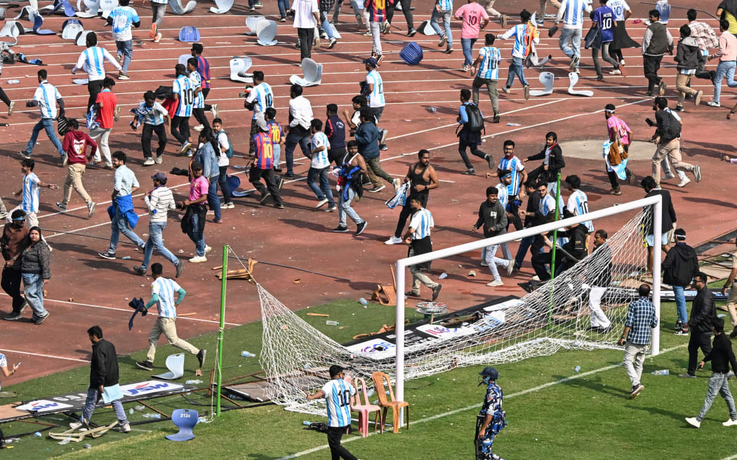 Security personnel try to control the crowd as Argentina's footballer Lionel Messi departs from Salt Lake Stadium during his GOAT Tour in Kolkata on December 13, 2025. Angry spectators broke down barricades and stormed the pitch at a stadium in India after football star Lionel Messi, who is on a three-day tour of the country, abruptly left the arena. As a part of a so-called GOAT Tour, the 38-year-old Argentina and Inter Miami superstar touched down in the eastern state of West Bengal early on December 13, greeted by a chorus of exuberant fans chanting his name. (Photo by Dibyangshu SARKAR / AFP)