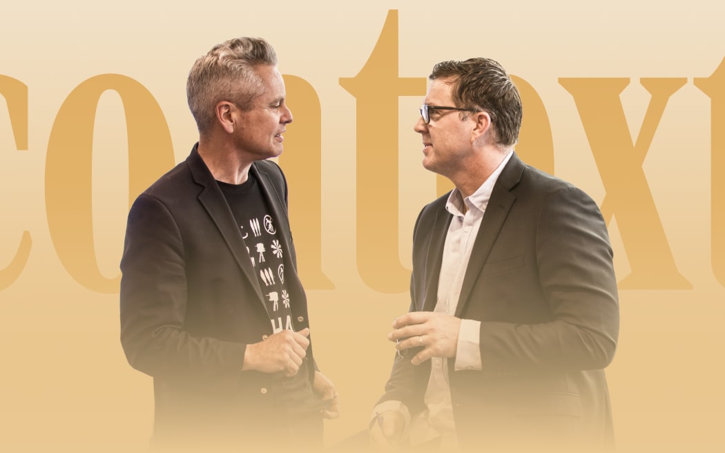 Two men converse intently way in front of large letters that read "Context"