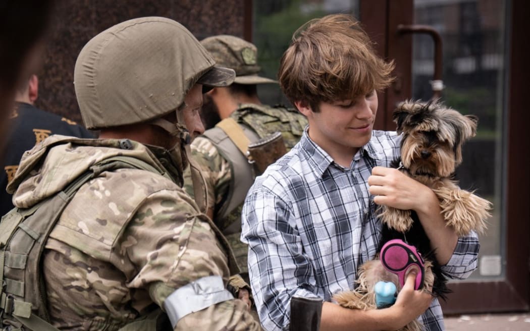 A local resident holds his dog as he speaks with a member of Wagner group in a street in the city of Rostov-on-Don, on June 24, 2023.
