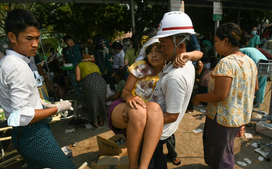 An earthquake survivor is carried as she waits to receive medical attention at a hospital in Naypyidaw on March 28, 2025, after an earthquake in central Myanmar. A powerful earthquake rocked central Myanmar on March 28, buckling roads in capital Naypyidaw, damaging buildings and forcing people to flee into the streets in neighbouring Thailand. (Photo by Sai Aung MAIN / AFP)