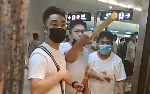This frame grab taken from video recorded on July 21, 2019 shows a mob of men in white T-shirts threatening pro-democracy protesters (out of frame at R on train) at Yuen Long station in Hong Kong.