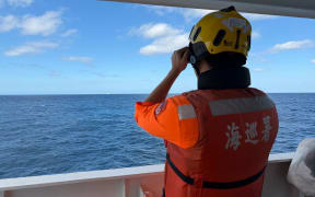 This handout photo taken and released on December 29, 2025, by the Taiwan Coast Guard shows a coast guard administration crew member observing Chinese coast guard ship No. 1303 from the CGA’s “Yilan” patrol vessel 23 nautical miles northwest of Pengjia Islet. Taiwan said on December 29, it has detected four Chinese coastguard ships near the democratic island's waters, as Beijing announced the start of live-fire drills (Photo by Handout / TAIWAN COAST GUARD / AFP) / RESTRICTED TO EDITORIAL USE - MANDATORY CREDIT "AFP PHOTO / TAIWAN COAST GUARD" - NO MARKETING NO ADVERTISING CAMPAIGNS - DISTRIBUTED AS A SERVICE TO CLIENTS
