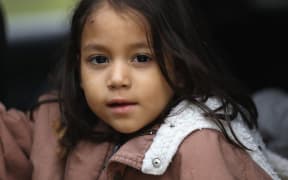 A Honduran immigrant child awaits transport by US Border Patrol agents after crossing with her family into the United States from Mexico.