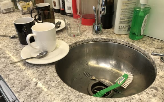An engineered stone bench, with dirty dishes on it.