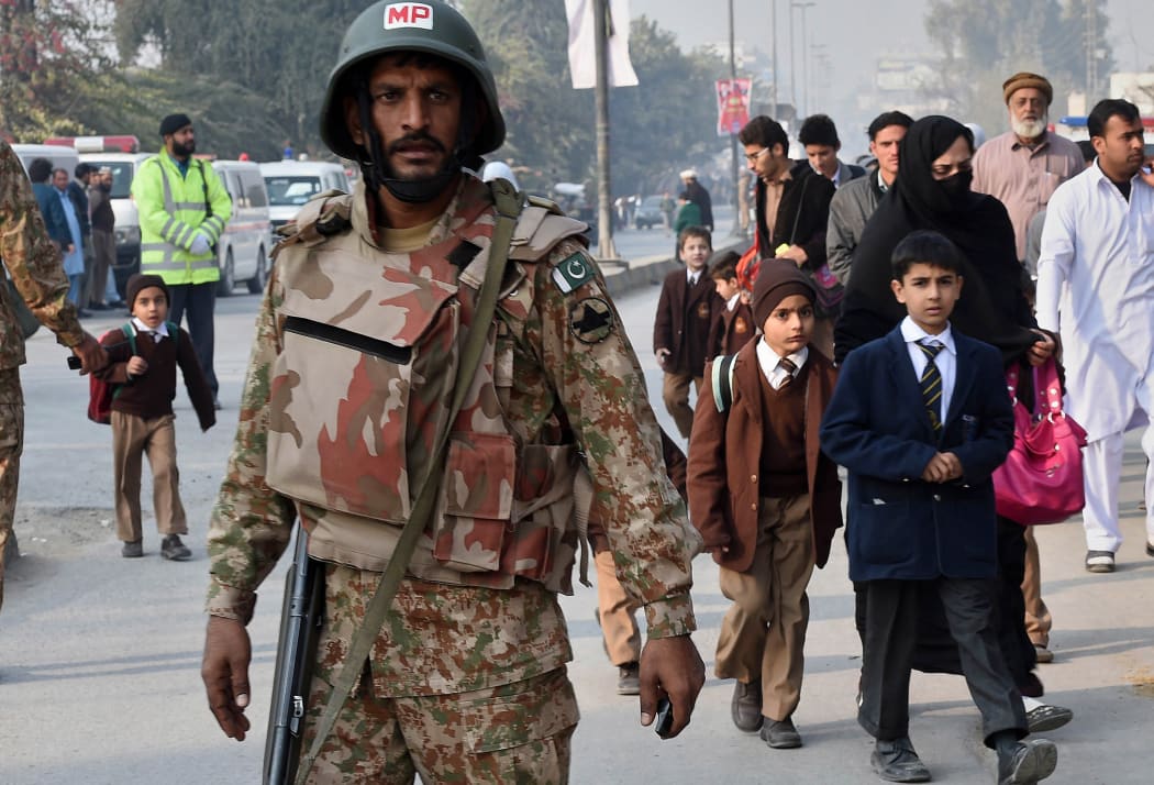 A soldier stands guard as parents and children leave the site of the attack.