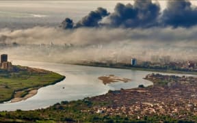 This video grab taken from AFPTV video footage on 19 April, 2023, shows an aerial view of black smoke covering the sky above the capital Khartoum.