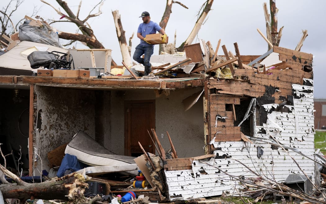 A man sorts through the remains of a home damaged by a tornado Tuesday, May 21, 2024, in Greenfield, Iowa. (AP Photo/Charlie Neibergall)