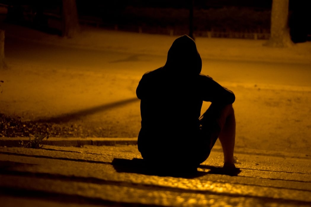 Hooded figure sitting on the road