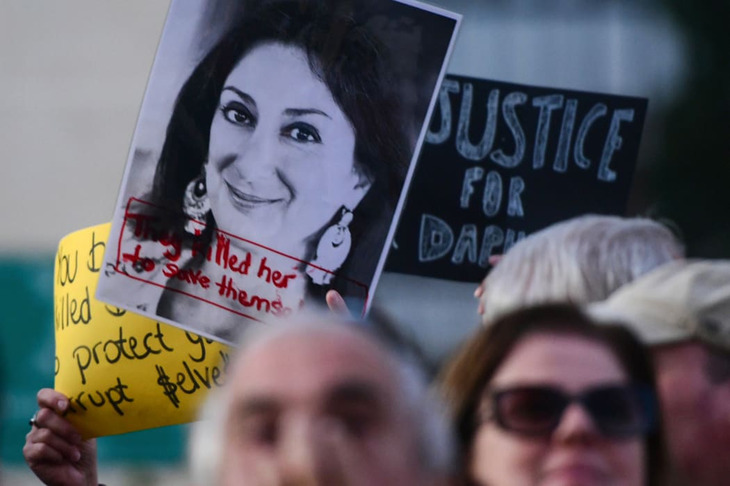 Protesters holding a photo of killed reporter Daphne Caruana Galizia gather outside Parliament in Valletta, Malta, on 26 November.