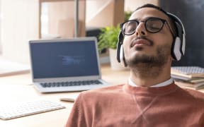 man in brown sweater with headphones on and eyes closed
