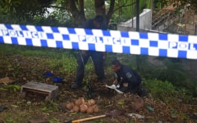 Officers from the police explosive ordnance disposal team inspecting the remaining pieces of the WW2 US 105mm high explosive projectile that killed one person and injured three others in Honiara. May 2021