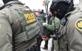 US Border Patrol agents detain a man in Minneapolis, Minnesota, on January 8, 2026. A US Immigration and Customs Enforcement (ICE) agent shot and killed an American woman on the streets of Minneapolis January 7, leading to huge protests and outrage from local leaders who rejected White House claims she was a domestic terrorist. The woman, identified in local media as 37-year-old Renee Nicole Good, was hit at point blank range as she apparently tried to drive away from agents who were crowding around her car, which they said was blocking their way. (Photo by Octavio JONES / AFP)