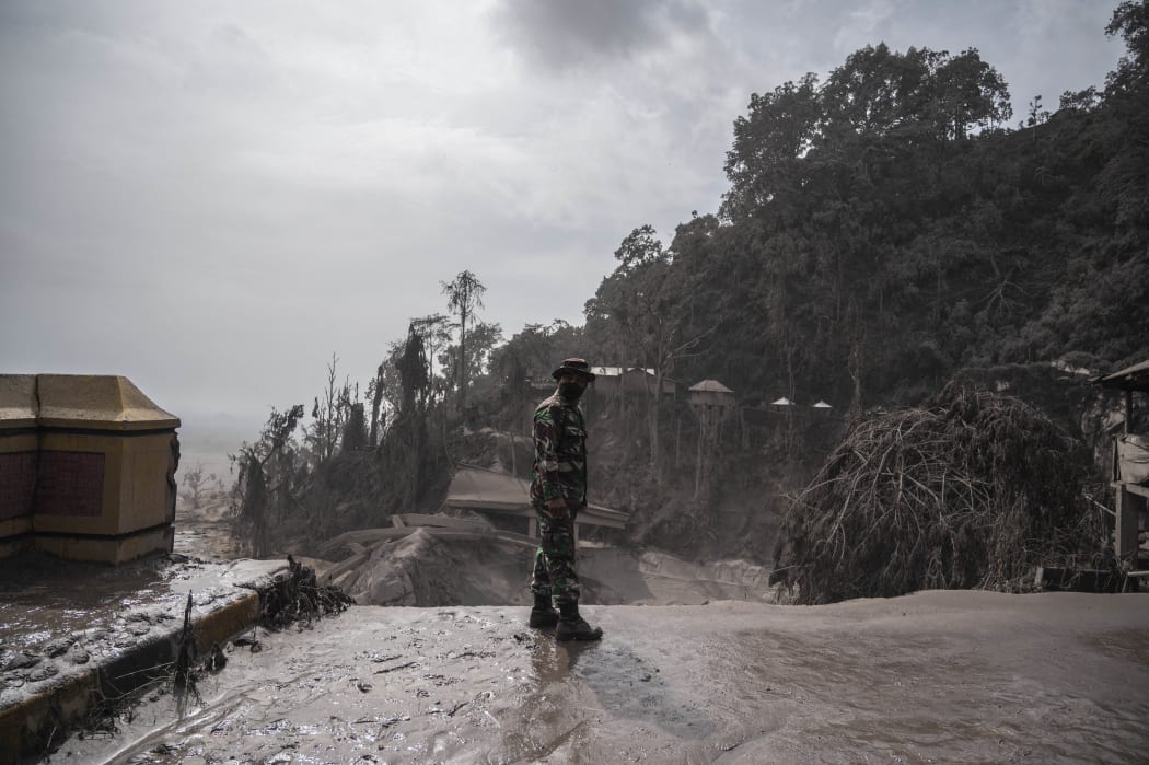A rescue personnel searches for villagers in an area covered in volcanic ash at Sumber Wuluh village in Lumajang.