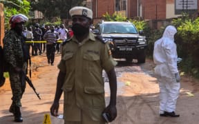 Police officers secure and investigate the crime scene with the car of General Katumba Wamala. Uganda's transport minister, who used to lead the armed forces, was shot Tuesday in an attack which left his daughter and bodyguard dead.