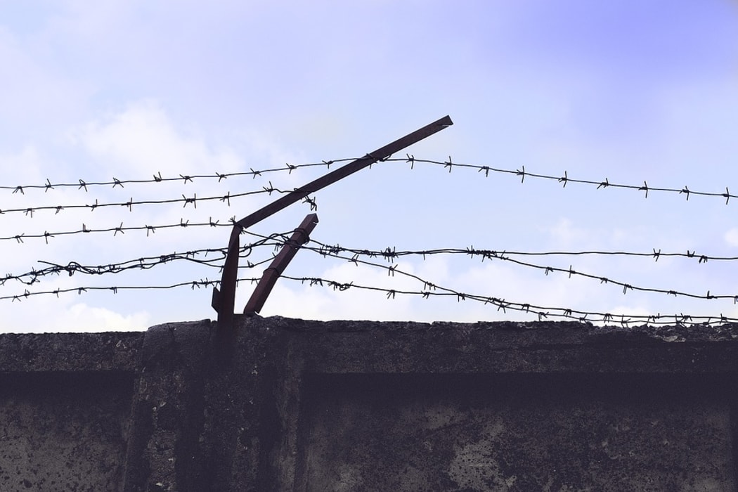 Barbed wire running along top of high wall