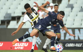 Ulises Davila of Macarthur FC and Steven Ugarkovic of the Phoenix challenge for the ball.