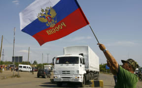 A Russian national flag is waved as  trucks cross the Ukrainian border at the Izvarino custom control checkpoint.