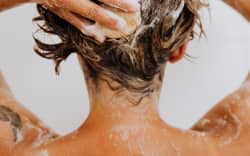 A woman washes her hair with shampoo.