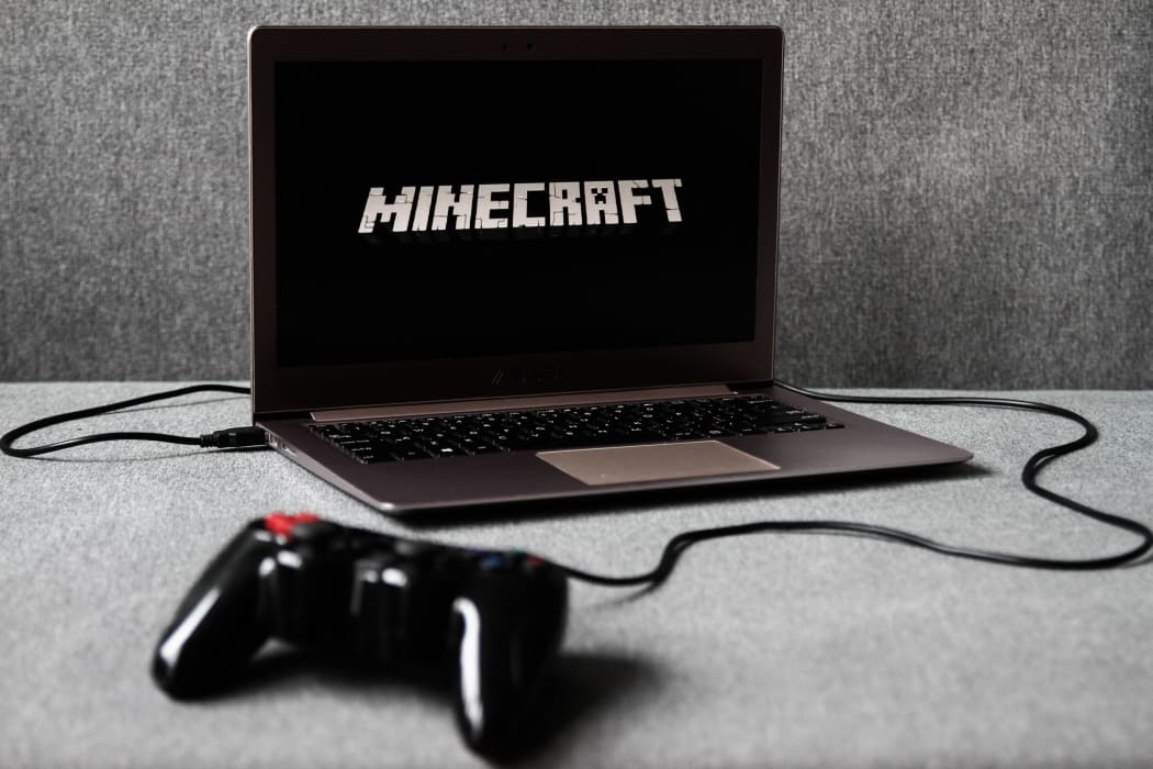 Minecraft logo displayed on a laptop screen and a gamepad are seen in this illustration photo taken in Krakow, Poland on August 5, 2021.