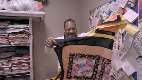 Missouri maximum security prisoner Chill, in Netflix documentary The Quilters, directed by Jennifer McShane, smiles as he holds up a quilted piece he's made.