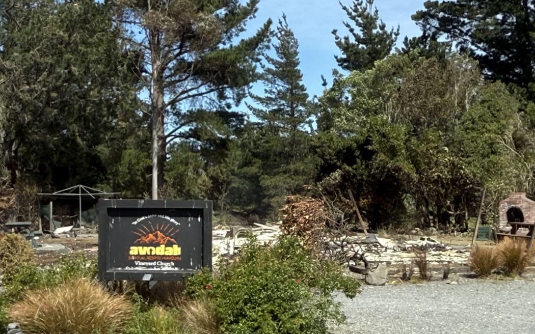 The Avodah Spiritual Respite sign in front of ashes where a house once stood.