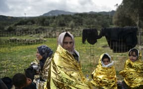 Migrant family waits for humanitarian aid on the Greek island of Lesbos after crossing with other migrants and refugees.