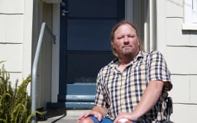 Shane Emeny sits at the front door of the state house he hopes to move into soon.