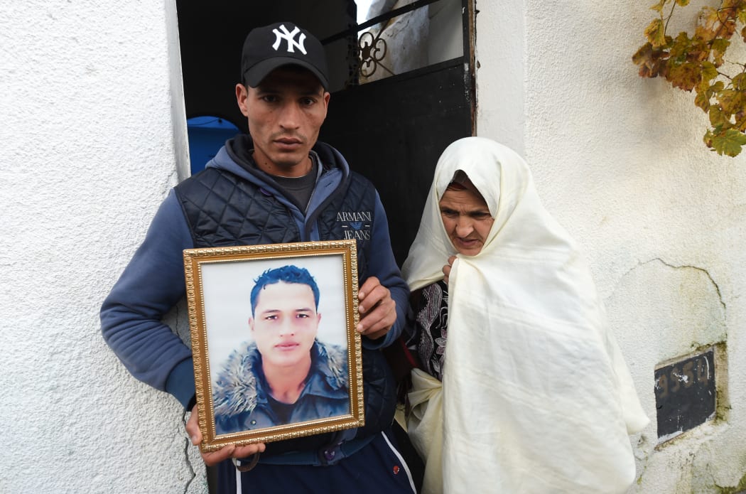 Walid Amri, the brother of Anis Amri who was the prime suspect in Berlin's deadly truck attack shot dead in Milan, poses with a portrait of his brother in front of the family house in the town of Oueslatia, in Tunisia's region of Kairouan.