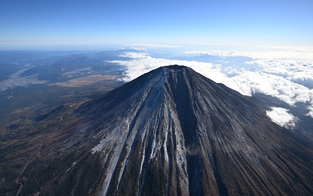 The first snowfall near the summit of Mount Fuji is observed above Yamanashi and Shizuoka Prefectures on November 7, 2024. The Kofu Regional Meteorological Observatory announced on November 7 that it had observed the first snowfall on Mount Fuji. This was 36 days later than the average to make the latest first snowfall in the past 130 years since statistics began being kept in 1894.( The Yomiuri Shimbun ) (Photo by Masahiro Sugimoto / Yomiuri / The Yomiuri Shimbun via AFP)