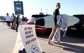 A surfer walks towards a polling station on Bondi Beach in Sydney on October 14, 2023, as polls open in Australia's historic Indigenous rights referendum. (Photo by DAVID GRAY / AFP)