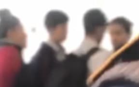 A screengrab from the video shows a group of students talking before another student approached the scene and attacked one of the young men.