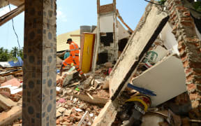 A rescue worker searches a quake damaged house at Pemenang village in northern Lombok, on 7 August, two days after the area was struck by an earthquake.