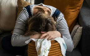 A woman slumps over a laundry basket.