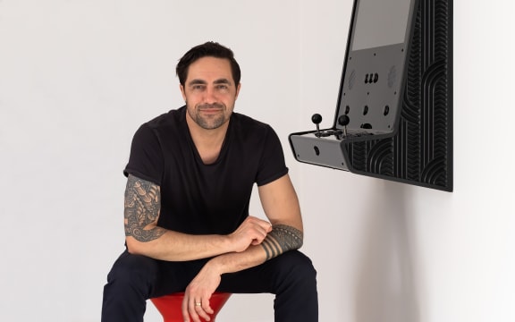 Animator Preston McNeil with an arcade game console created in collaboration with artist Joe Sheehan