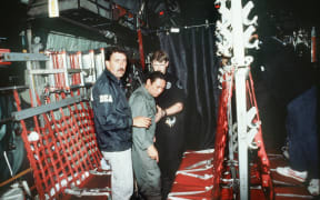 In this photo released 04 January 1990 by the Defense Department, Panamian General Manuel Noriega (C) is brought on board a US military plane 3 January 1990 for a flight to Miami after his arrest. (Photo by AFP)