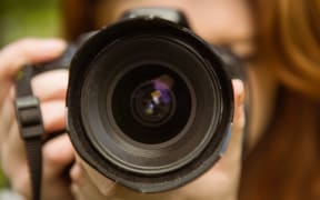 A photographer holds up her camera to take a shot (file)