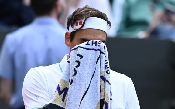 Switzerland's Roger Federer uses a towel during a break in play against Poland's Hubert Hurkacz during their men's quarter-finals match on the ninth day of the 2021 Wimbledon Championships at The All England Tennis Club in Wimbledon, southwest London, on July 7, 2021.