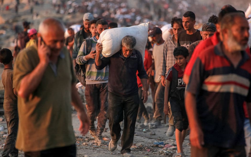 People carrying sacks of flour walk along al-Rashid street in western Jabalia on June 17, 2025, after humanitarian aid trucks reportedly entered the northern Gaza Strip through the Israeli-controlled Zikim border crossing, amid the ongoing war between Israel and Hamas.