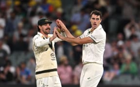 Australian bowler Pat Cummins (right) reacts with Travis Head after dismissing Indian batsman Rohit Sharma for 6 runs on day two of the Second Test match between Australia and India at Adelaide Oval in Adelaide, Saturday, December 7, 2024.