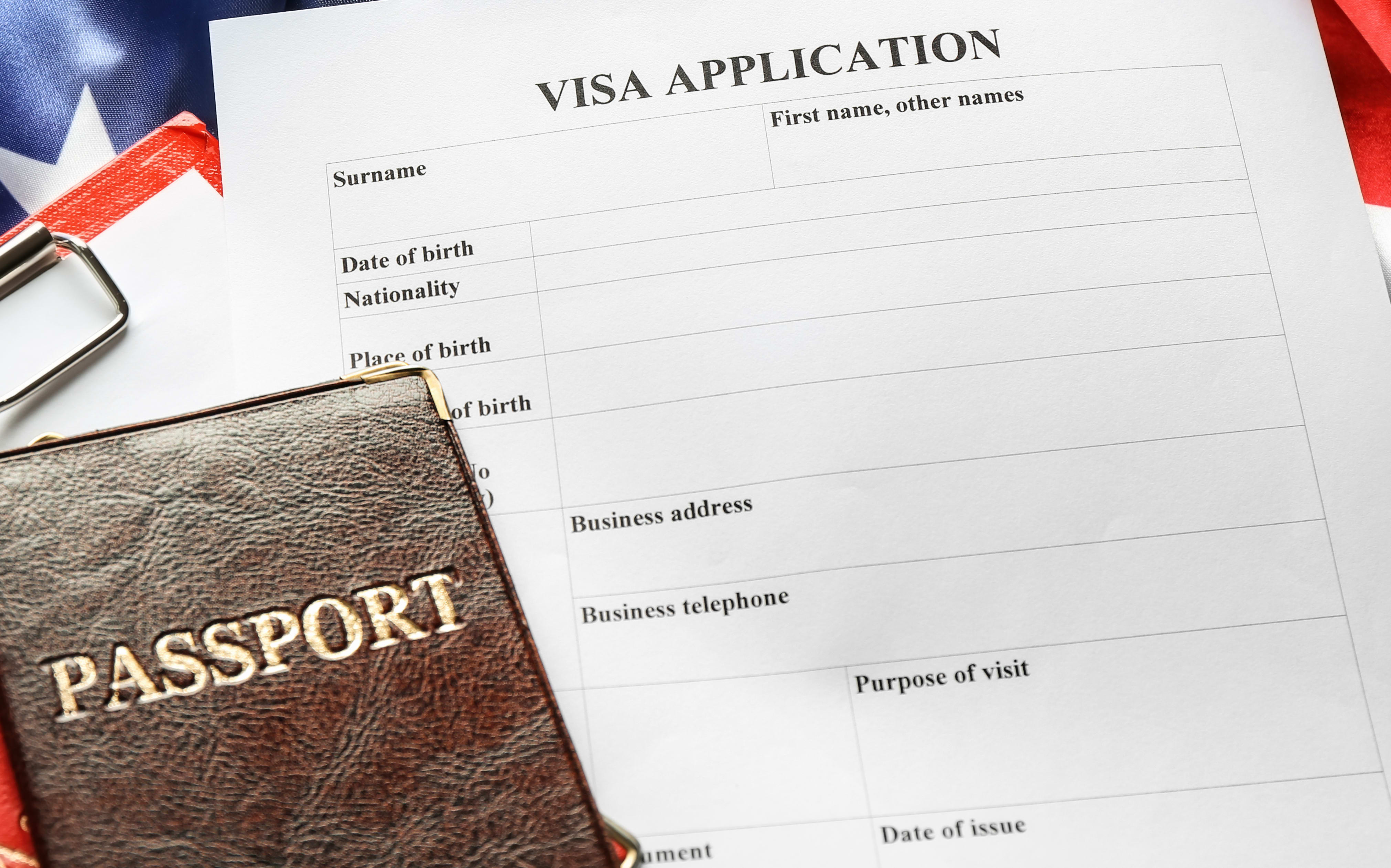 Passports, American flag and visa application form on table. Immigration to USA.