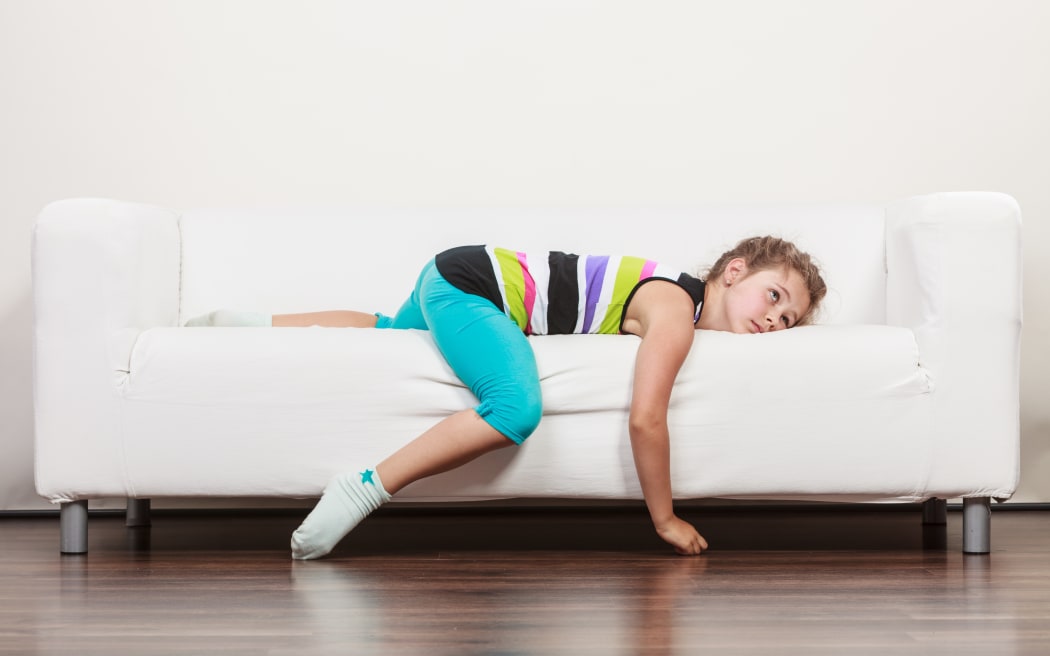 Fatiguée, épuisée, paresseuse, petite fille allongée sur un canapé à la maison.  Enfant endormi se reposant sur un canapé.