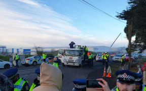 Police arrest a a woman after she jumped on a Fletchers truck at Ihumātao this morning.
