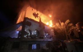 People use the lights on their telephones to search for victims amid the rubble of a smouldering building, following an Israeli strike in Rafah in the southern Gaza Strip on December 6, 2023. Israeli forces on December 6 battled Hamas militants in Gaza's main southern city Khan Yunis, leading to "deepening horror" for civilians, the UN said, after nearly two months of war sparked by deadly attacks on Israel.