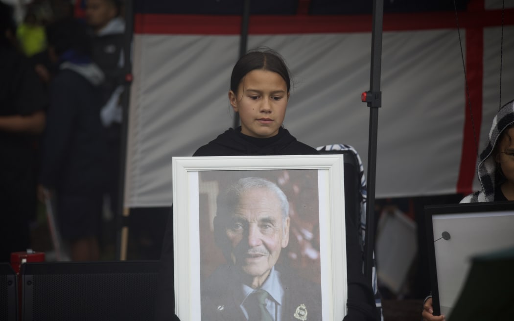 Young wāhine holds a picture of Māori war hero Robert 'Bom' Gillies, who died the week before the hīkoi began.