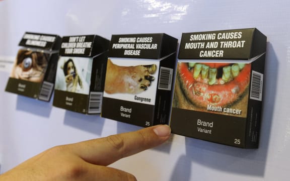 A man points at proposed cigarette packaging by the World Health Organization (WHO) showing various ailments caused by cigarette smoking, displayed at the WHO office in Manila on October 10, 2011. The World Health Organization's chief on October 10 urged governments to unite against "big tobacco", as she accused the industry of dirty tricks, bullying and immorality in its quest to keep people smoking.