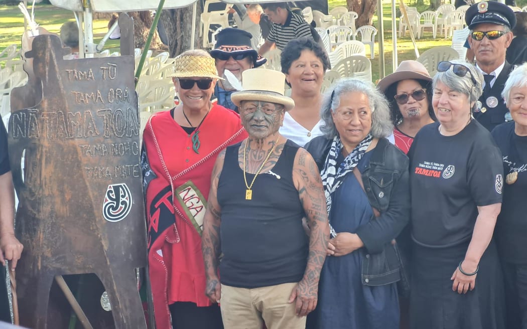 Tame Iti standing beside the sculpture named Ngā Tamatoa which he gifted to Waitangi.