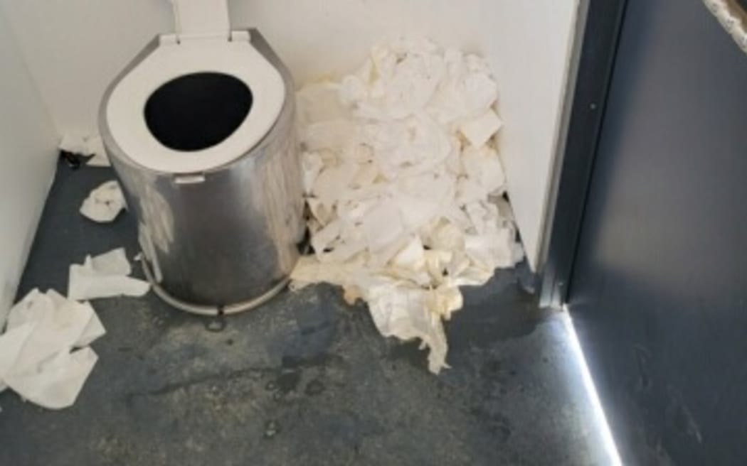 Photo of a DOC toilet with toilet paper piled up